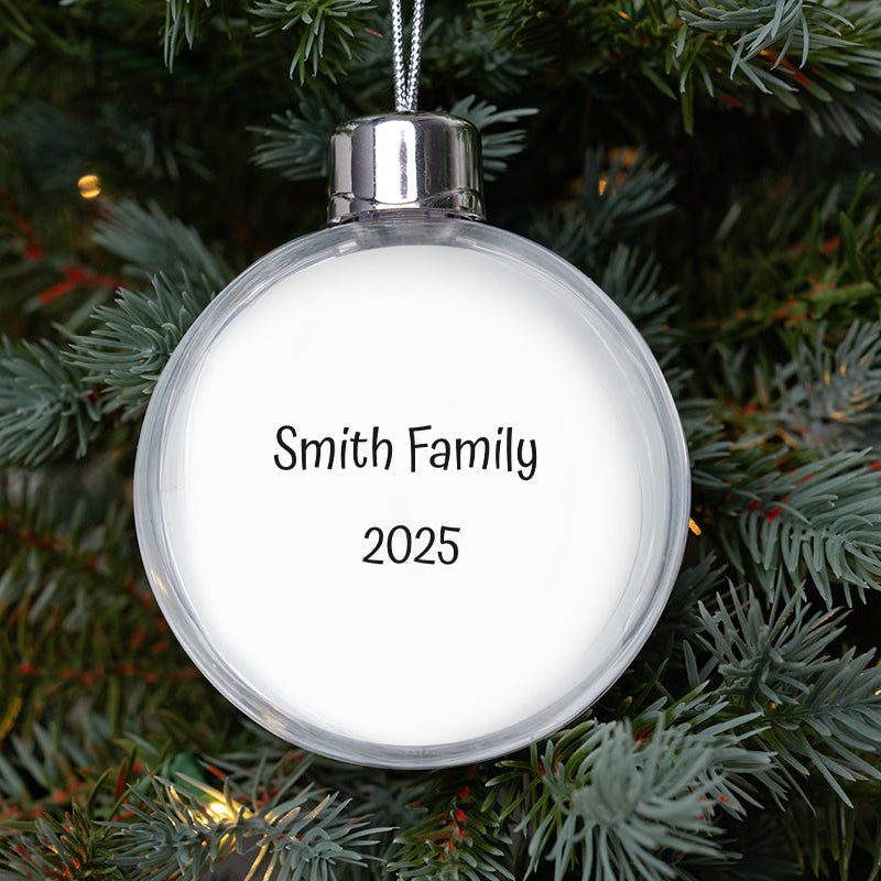Round white ornament with 'Smith Family 2025' text on a Christmas tree.